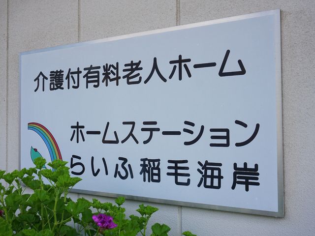 施設の看板と緑の植物 ロゴ 明るくポップなデザインの看板が、心地よい環境を象徴しています。利用者の方々が日々過ごされる場所の一端を感じ取ることができます。