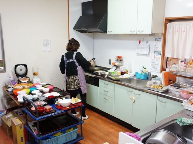 キッチンで調理中の人 調理場 清潔感あるキッチンでスタッフが丁寧に料理をしています。食事準備の様子は、心を込めた手作りの温もりを感じさせます。