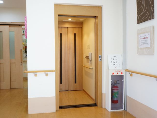 廊下と部屋の開口部 エレベーター 温かみのある木目調で統一された廊下がお出迎えします。利便性を配慮した手すりが設置されています。
