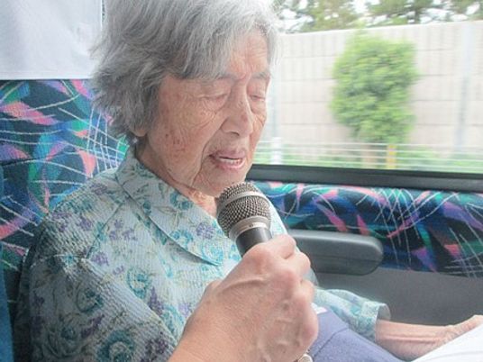 マイクを持つ高齢女性