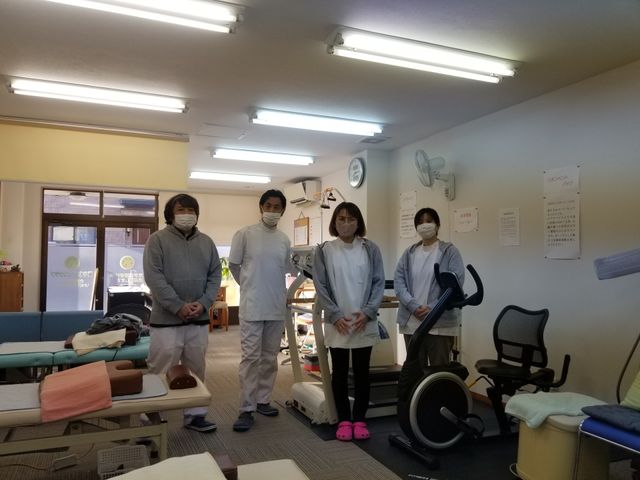スタッフ立つ機能訓練室 機能訓練室 職員が立ち並ぶ、日当たりの良い明るい訓練室です。様々なリハビリ機器が整っており、充実したサポートが受けられます。