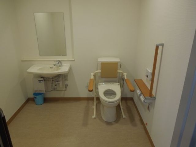 広々とした洗練されたトイレ 洗面台・トイレ 手すりが付いた清潔感のあふれるトイレで、安心して日常の生活を送ることができます。ゆとりを持って設計された空間です。