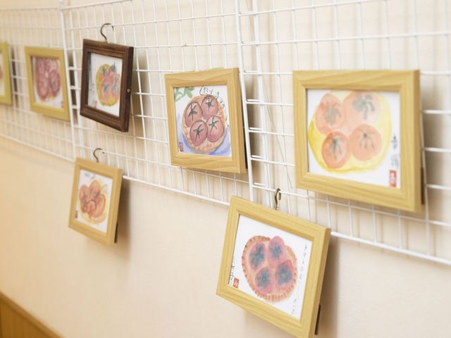 廊下の壁に飾り額 廊下   明るい廊下の壁に、利用者の作品と思われる額が並んでいます。歩きながら作品を楽しめる、温かい雰囲気の通路です。