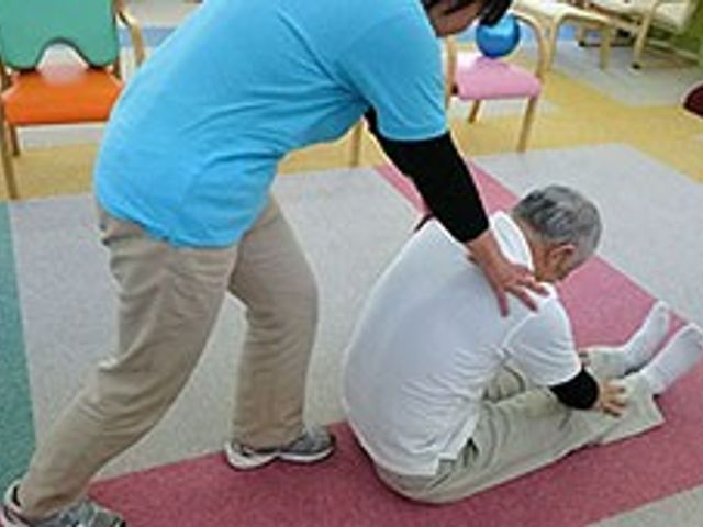 ストレッチをする室内 機能訓練室 利用者の方がリハビリを行う様子です。専門スタッフが丁寧にサポートしています。