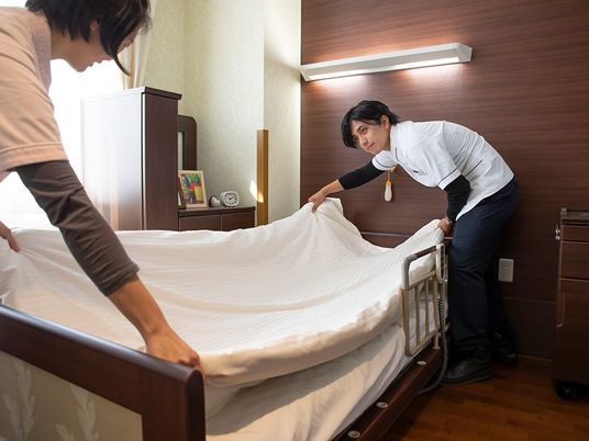 居室でシーツを整える様子  