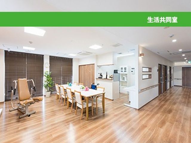 明るい生活共用室 リビング   自然光が入り、木目調の床が広がる明るい共有空間です。食卓やくつろぎの椅子があり、ゆったり過ごしやすい雰囲気です。