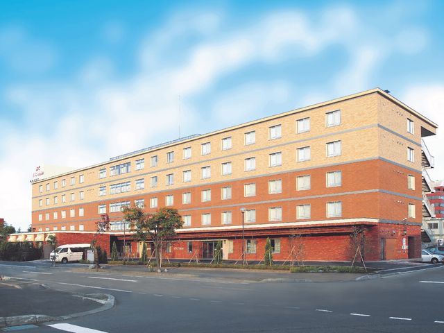 オレンジ色の外壁の建物 外観 明るい外壁と清潔な周辺環境が印象的です。通勤に便利な立地で、充実した職場環境を提供します。