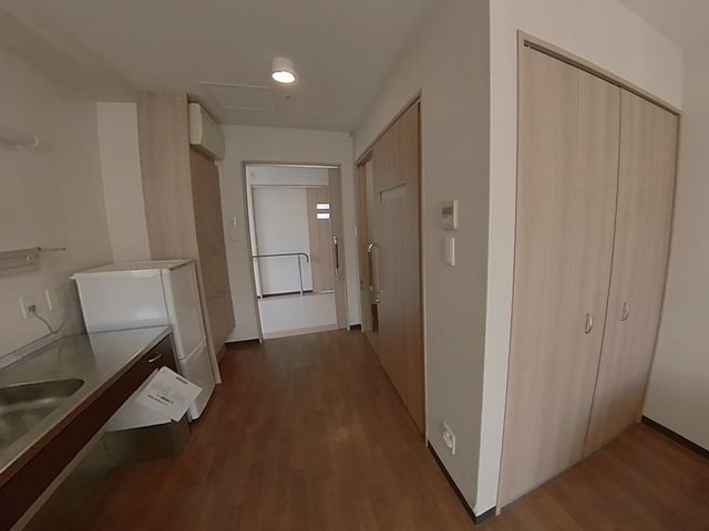 洋室のキッチンと入口 居室 モダンな居室は充実した設備が整っており、手すりも設置された広々とした入口が特徴です。日々の暮らしを支える快適な環境を提供しております。