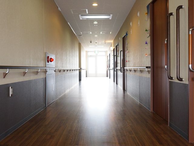 明るい廊下の風景 廊下 床には木目調の素材を使用し、手すりが整備された廊下です。壁には彩りを加える装飾が施されています。