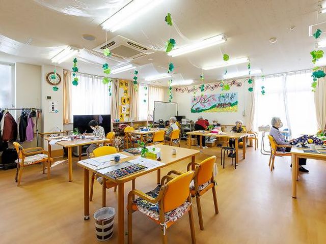 活動中の多目的室 多目的室 複数のテーブルが並び、利用者がそれぞれの活動に集中しています。手芸や読書など、趣味の時間をお過ごしいただける空間です。