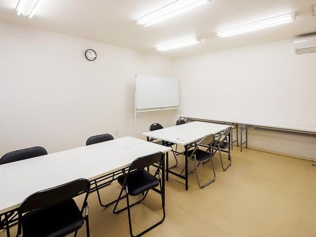 清潔感ある多目的室 多目的室 機能的な空間の多目的室です。壁に掛けられた時計の下、ミーティングや講座に使えそうなテーブルと椅子が並んでいます。