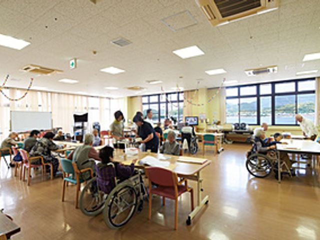 窓の大きな多目的室 多目的室 自然光が豊かに差し込む広々とした空間で、日常の活動を快適にサポートしています。スタッフと利用者が楽しそうに交流しています。