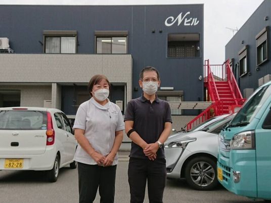 スタッフの立ち姿と建物外観  