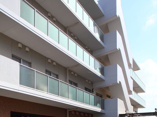 白と茶の建物エントランス 非常用外階段 開放的なエントランスを持つ清潔でモダンな建物です。将来の職場として、快適な環境で働けることを想像してみませんか。