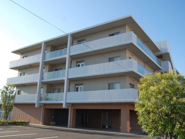 多階層の外観 駐車場 広々とした駐車場を備え、清潔感のあるモダンな建物です。将来を見据えた就業場所をお探しの方に適しています。