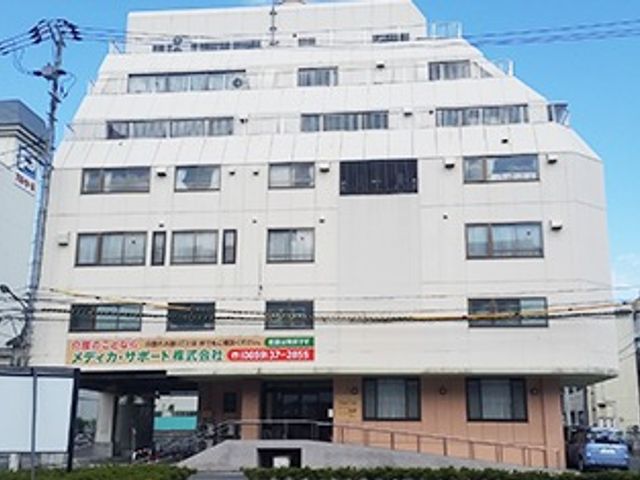 白い外壁の建物外観 外観 清潔感のある白い外壁が印象的な建物です。通りからもアクセスしやすい立地で、働きやすい環境が整っています。