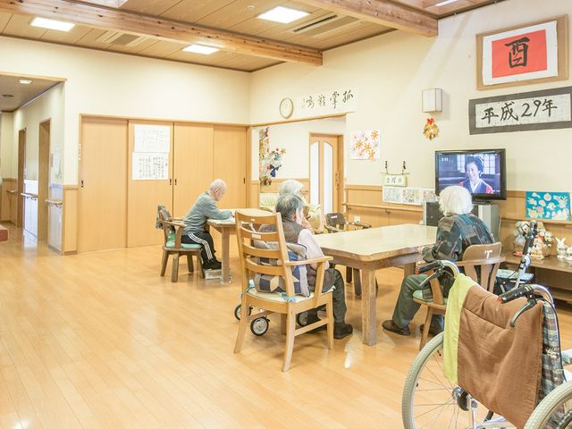 明るい共有スペース ラウンジ 広々とした明るい空間で、居住者がテレビを楽しんでいます。車椅子の利用者も快適です。