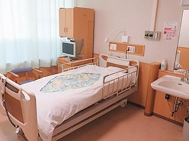 ベッドと洗面台の室内 居室 コンパクトで快適な居室です。個別のベッドと洗面台が設置され、プライバシーが保たれています。