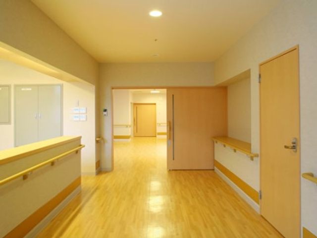 温かみのある廊下 サービスステーション 明るく広々とした廊下は、ゆったりとした歩行スペースを提供しており、安全かつ快適な移動を支援します。