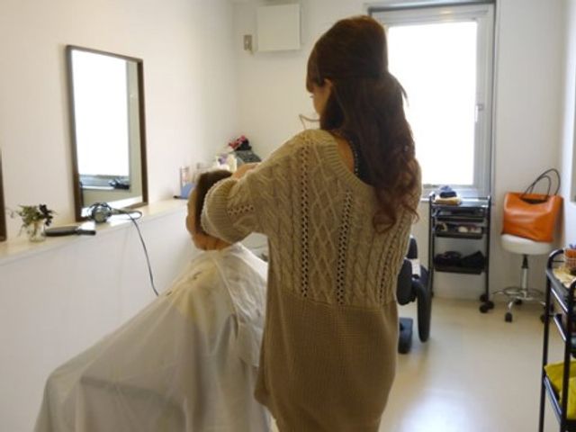 美容のお手入れを受ける人 理美容室 清潔感のあふれる理美容室で、利用者様が丁寧なヘアケアを受けてらっしゃいます。スタッフが優しく対応しており、明るく落ち着いた雰囲気です。