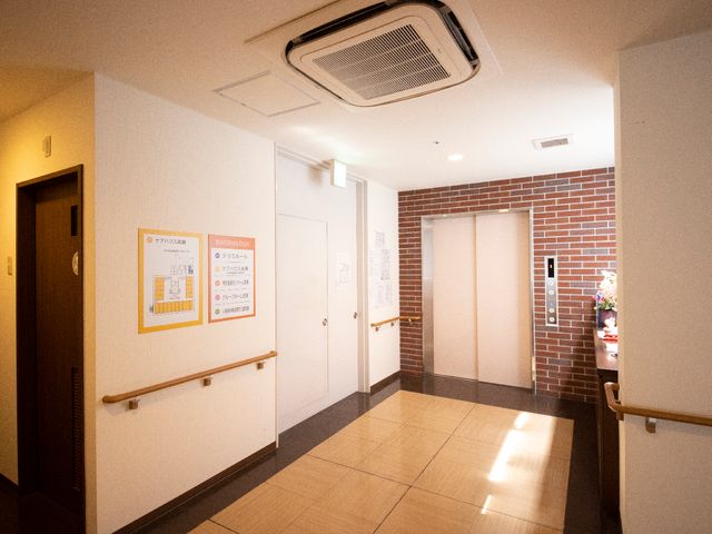 廊下と掲示物の様子 エレベーター 掲示物がある明るく清潔な通路です。手すりが設置されており、安全に配慮された設計となっています。