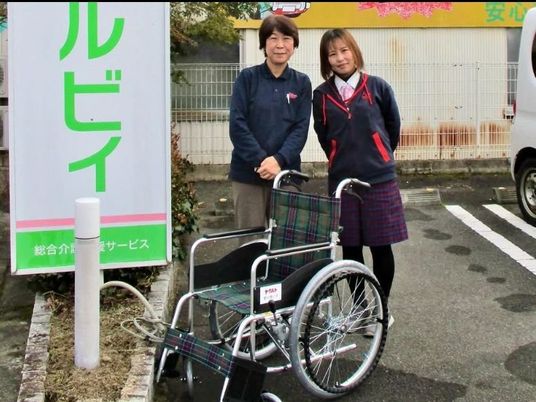 スタッフ2人と車椅子の玄関前  