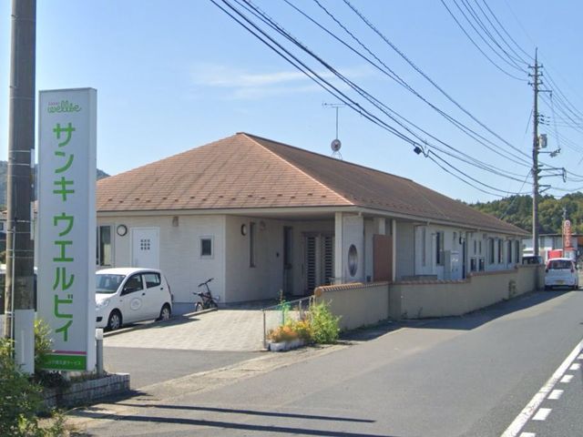 広い駐車場の施設外観 外観 広々とした駐車スペースがある、明るい屋根の建物です。周囲には緑が広がっています。