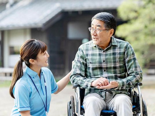 車椅子に乗った高齢男性と付き添いの女性介護士