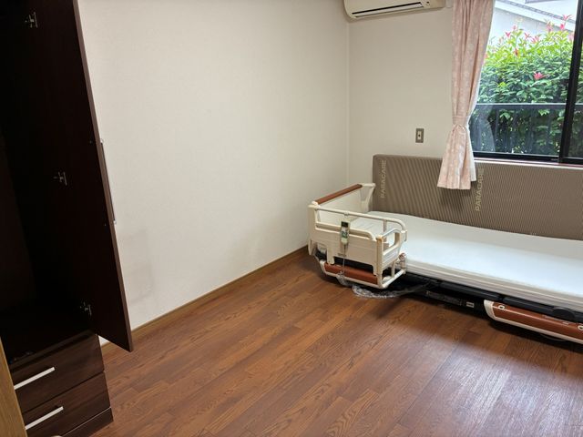 明るい居室のベッド 居室   木目調の床とやわらかな光が入る落ち着いた居室です。介助しやすい電動ベッドがあり、ゆったり過ごせそうです。