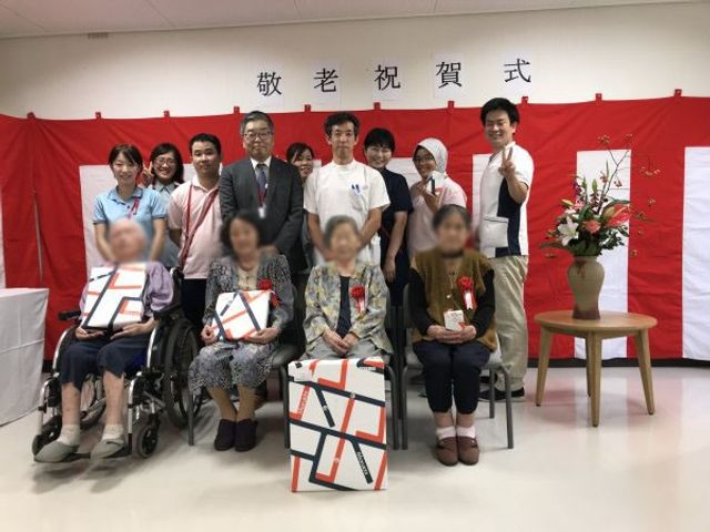 集合写真 理美容室 敬老のイベントを祝う人々が集まっています。笑顔で和やかな雰囲気の中、皆で記念写真を撮影しています。