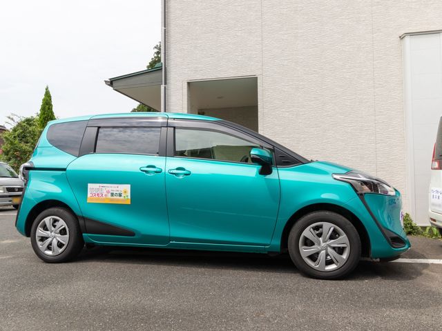 青い車と建物の外観 車 この施設には専用の車両があり、外出時のサポートも充実しています。利用者様の快適な移動をお手伝いします。