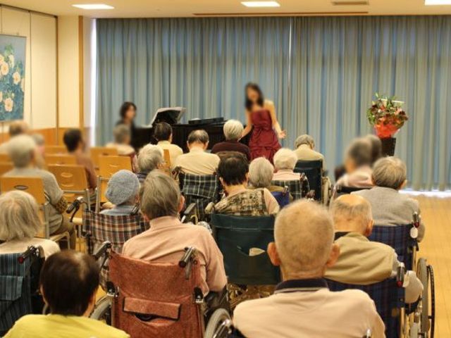 イベント中の多目的室 多目的室 演奏会が行われており、多くの利用者がリラックスした雰囲気で参加しています。