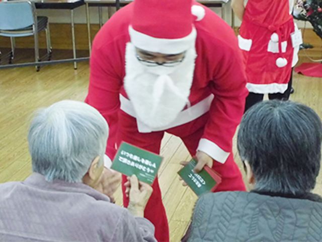 交流を楽しむ様子 居室 サンタ衣装のスタッフが、お年寄りと交流を図っています。温かみのある空間です。