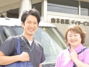 笑顔のスタッフ送迎車前  