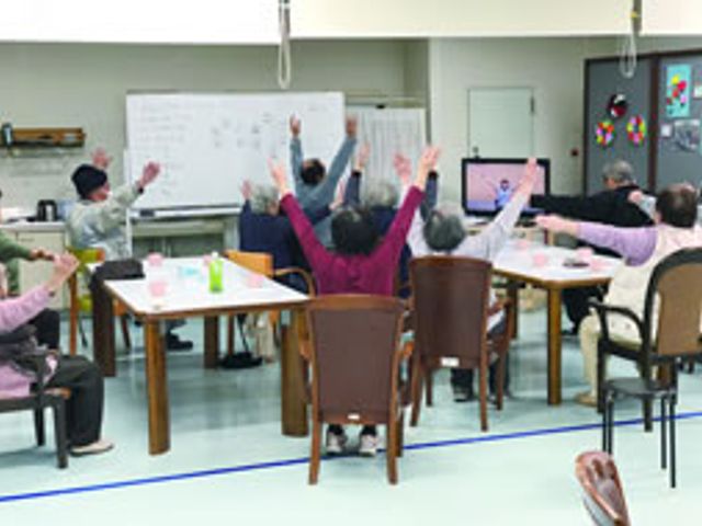 体操をする人々の居室 居室   椅子に座りながら体操を楽しむ様子です。リラックスした雰囲気で、交流も深まります。