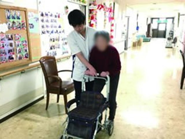 廊下での介助 廊下 明るい廊下で、スタッフが歩行をサポートしています。温かな雰囲気で安心感があります。