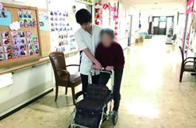 廊下での介助 廊下 明るい廊下で、スタッフが歩行をサポートしています。温かな雰囲気で安心感があります。