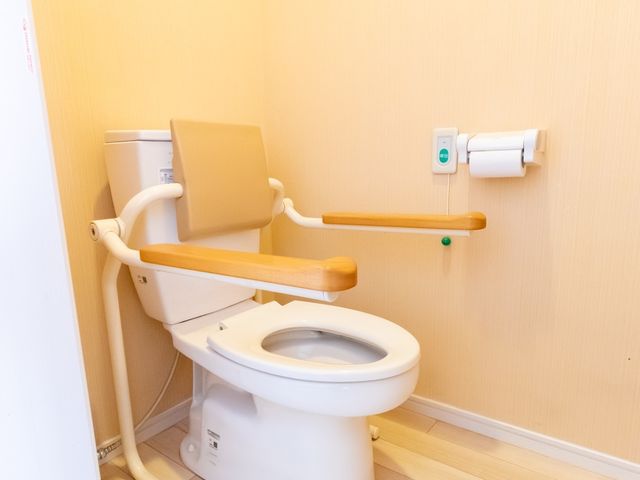 バリアフリートイレ設備 トイレ 手すり付きで安全なトイレです。自立支援のための配慮が行き届いており、設備面でのサポート体制が整っています。