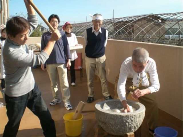 屋外でのもちつきイベント イベント 屋上で餅つきが楽しめる光景です。笑顔があふれる人々の温かい雰囲気が感じられます。
