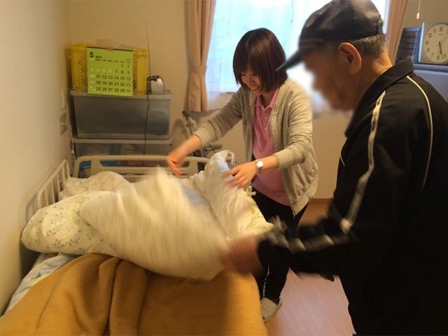 ベッドメイキングの様子 居室 スタッフがベッドメイキングを行う和やかな居室です。日差しが差し込み、明るい環境です。