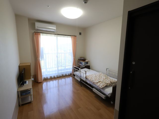 清潔感のある居室 居室 日差しが入るあたたかい雰囲気のお部屋です。窓際にはベッドとテレビが備えられ、快適な生活空間となっています。