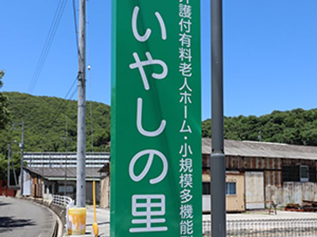 緑の看板と周囲の様子 看板 緑色の看板が立つ風景です。緑豊かな環境の中に溶け込むように存在感を放っています。