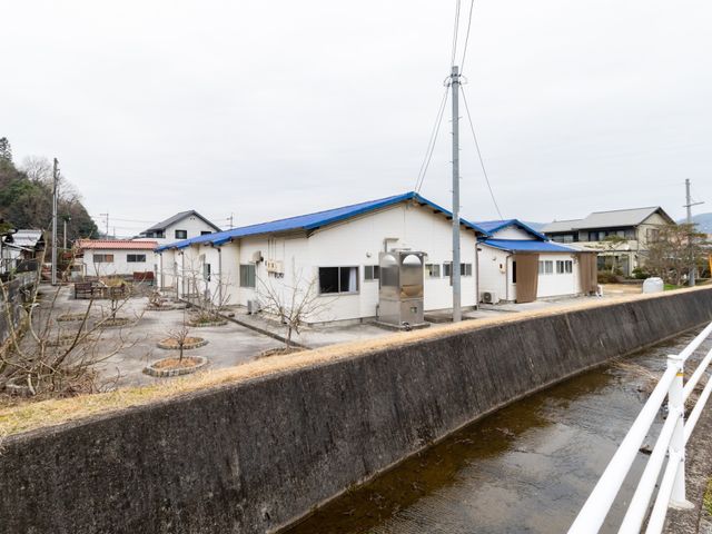 青い屋根の建物一画 外観 静かな環境にある明るい建物は、自然溢れるロケーションで働く心地よさを提供します。