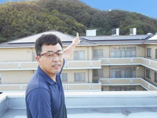 施設外観を指す男性  