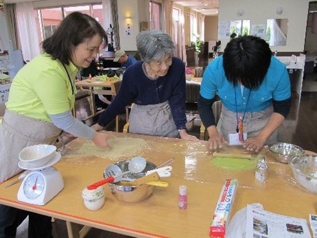 料理活動をする人々 日常２ 笑顔で料理を楽しむスタッフと利用者様の姿が見られ、暖かいコミュニケーションが芽生える場です。