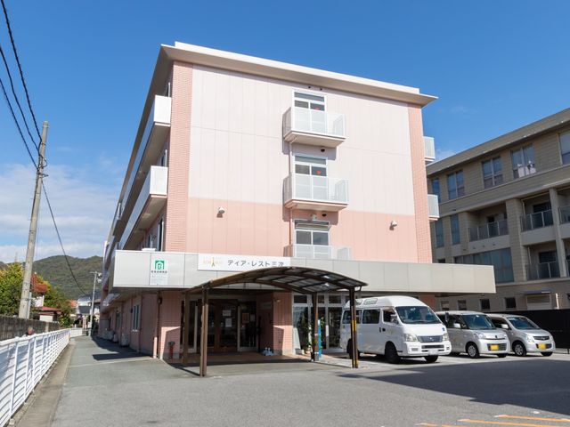 ピンク色の建物正面ファサード 外観 明るいピンク色の外壁が印象的な建物です。ゆったりとした出入り口が、訪れる全ての人に開かれた雰囲気を提供します。