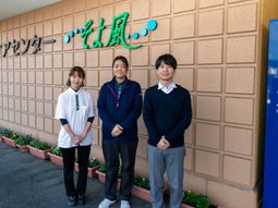 スタッフが笑顔で立つ看板前