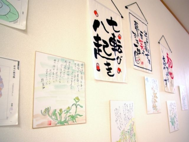 掲示物が並ぶ壁 掲示物 色紙やカラフルなポスターが壁を飾るスペースです。入所者が自分の作品を展示しています。