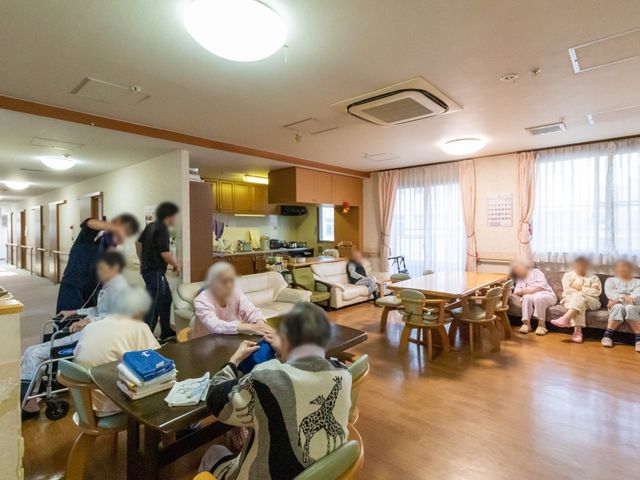 共用スペース内装と配置 共有スペース ゆったりとしたソファが並ぶ共用ラウンジは、利用者同士の交流の場としても最適です。スタッフと利用者が一緒にいる様子から、温かみのある雰囲気が感じられます。