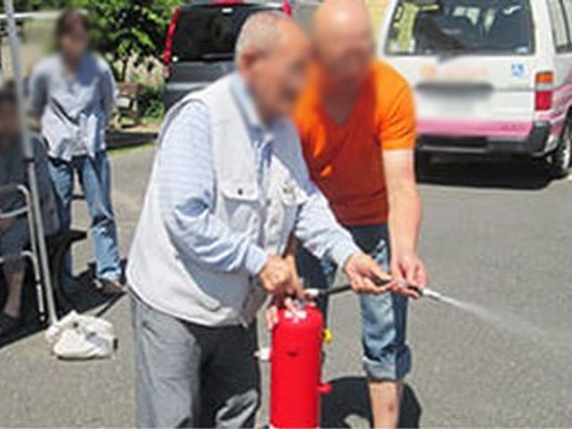 防災訓練の様子 外観 屋外で防災訓練が行われ、消防器具の使用方法が実演されています。施設の安全対策を学べます。